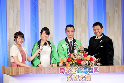 CMについてインタビューする渡辺徹さん（右）、 森遥香アナ（左）、大賞を受賞した大崎市の皆さん